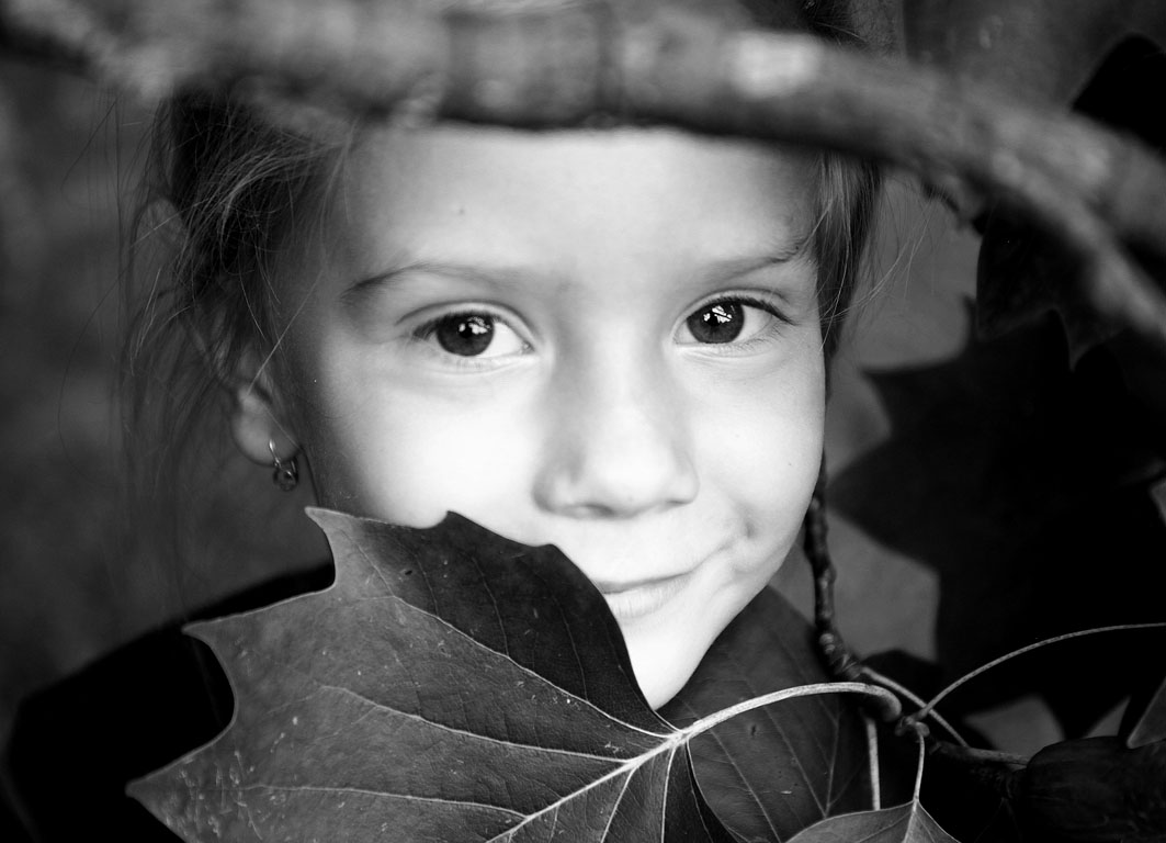 Čiernobiela fotografia dievčatka ukrytého v kríkoch - detail